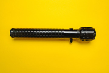 Travel and Search. Close-up of a flashlight on yellow background.