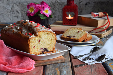Dried fruit cake with raisins, apricots, cherry and glass of red wine, bottle and flower rustic wooden background. Valentines day still life. Sliced freshly baked fruitcake. Copy space for text