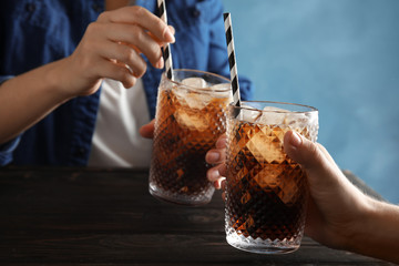 Friends with glasses of tasty refreshing cola at table, closeup view - obrazy, fototapety, plakaty