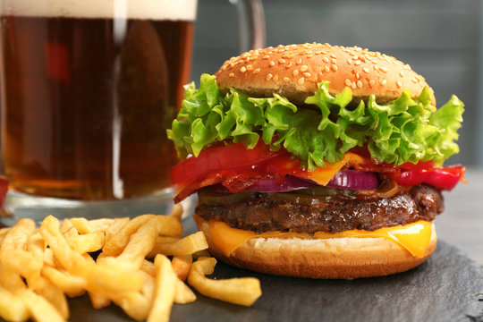Burger with bacon and french fries on slate plate, closeup