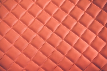 Close up of rhombus pattern with red stitch lines on red leather car seat upholstery background