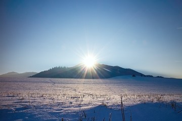 Winter sun rays over snowy meadow in Liptov. Poludnica in the background.