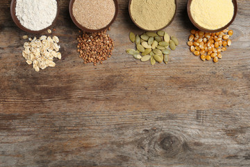 Flat lay composition with different types of flour and seeds on wooden background. Space for text