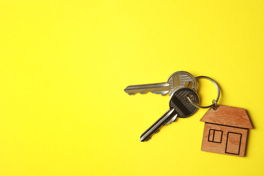 House keys with trinket on color background, top view. Space for text