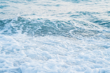 Sea waves in the sunset light roll on the seashore, covered with small pebbles