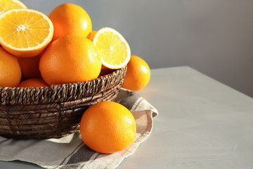 Fresh juicy oranges in wicker basket on table. Space for text