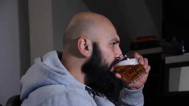 close up of young man drinking a glass of beer at home.
