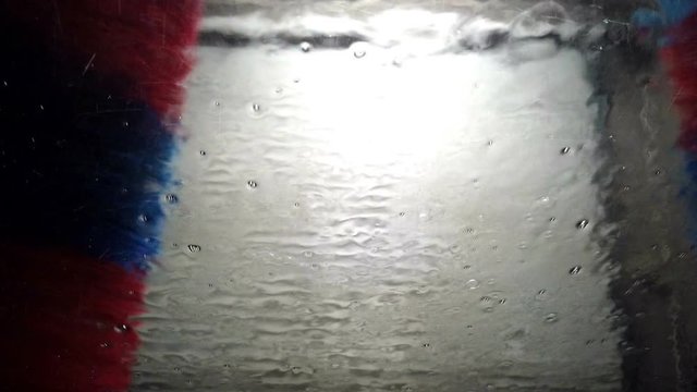 View from inside of car while washing it in automatic car washer. Filming while sitting in car between car wash.