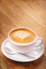 Cup of fresh cappuccino coffee on the wooden table