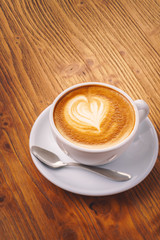 Cup of fresh cappuccino coffee on the wooden table