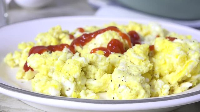 Pouring catsup over scrambled eggs slow motion