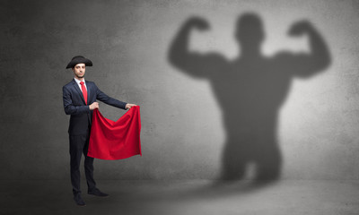 Businessman standing with red cloth on his hand and strong hero shadow on the background
