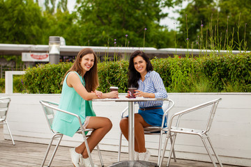 Two cheerful brunette women resting summer cafe