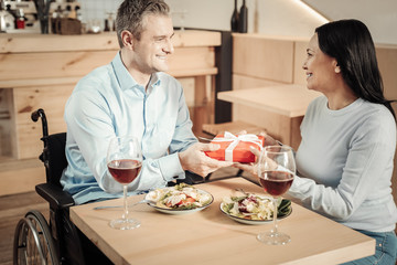 Attractive man in wheelchair giving a gift