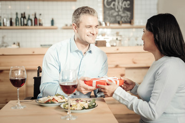 Smiling man presenting a gift to his woman