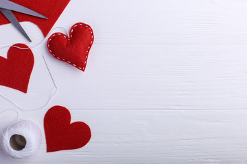 Handmade red felt heart next to threads and a needle on a white table. Women's Day Concept, Copy Space.