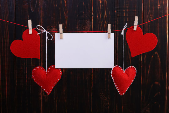 Handmade red felt hearts and white paper hanging on a rope with clothespins. Concept, banner, copy space, form. - Powered by Adobe