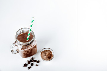 A glass of protein with cocoa and powder on a white background