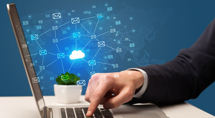 Businessman hand sending a bunch of messages on laptop with cloud computing concept
