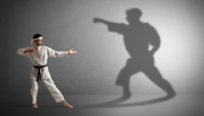Young karate man confronting with his own shadow
