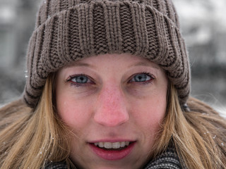 close-up of young german blonde girl with clear eyes and with cap in the snow.