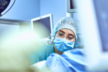 Young Female Surgeon with Medical Team in Back on Surgery