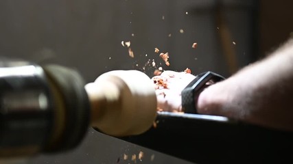 woodturning of handcrafter on turnery machine with flying wood shavings
