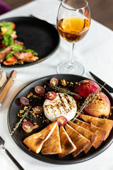 Grilled camembert with baked apple and grapes with slices of bread cakes