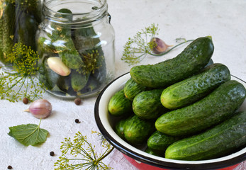 Fresh cucumber in metal bowl. Making of conservation from organic vegetables on a light background. Homemade organic green pickles in a jar. Copy space.