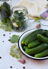 Fresh cucumber in metal bowl. Making of conservation from organic vegetables on a light background. Homemade organic green pickles in a jar. Copy space.