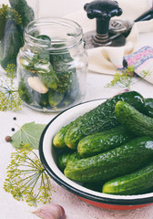 Fresh cucumber in metal bowl. Making of conservation from organic vegetables on a light background. Homemade organic green pickles in a jar. Copy space.