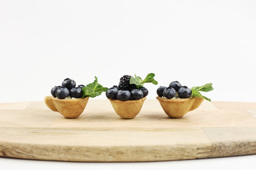 Blueberries in the cups of the dough on a wooden background