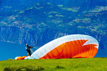 Unidentifiable paragliders preparing for the tandem flight on Monte Baldo mountain, Italy with Lake...