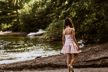 Little girl walking on the lake shore in summer