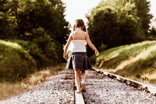 Rear view of girl balancing on railroad