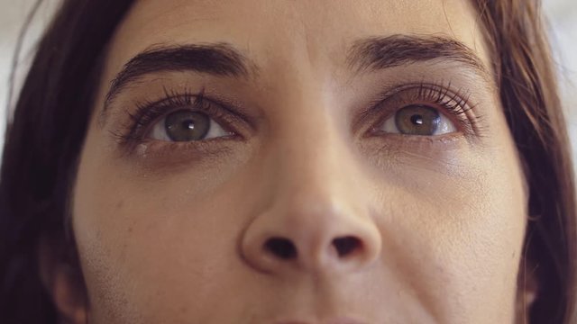 Serious young brunette woman's eyes looking just above camera - closeup