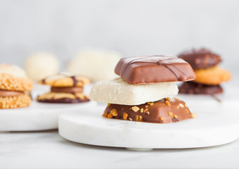 Luxury belgian chocolate and biscuit cookies selection on marble coasters and white kitchen table...