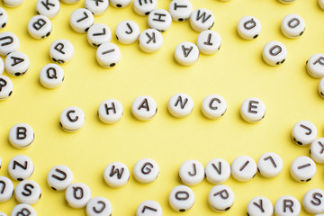 Word CHANCE made of plastic blocks on a yellow background with many letters around