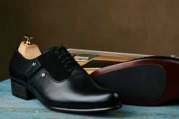 Leather mens shoes and bass guitar over brown background with copy space