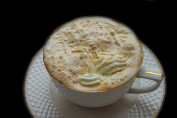 white cup with hot coffee and whipped cream on a black background