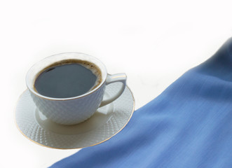 white cup with hot coffee on the windowsill on a white background next to a winter scarf