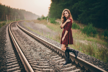 Beautiful sad thoughtful girl with curly natural hair on nature in forest on railway. Dreamer lady...