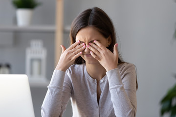 Tired teen girl rubbing dry irritable eyes feel eye strain tension migraine after computer work,...