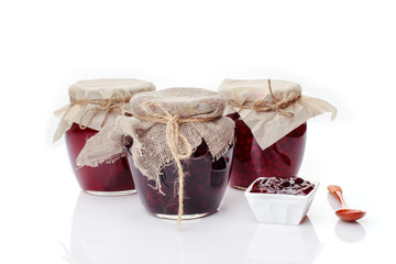 Set of glass jars with different types of homemade jam on white background. Harvest preservation and canning concept