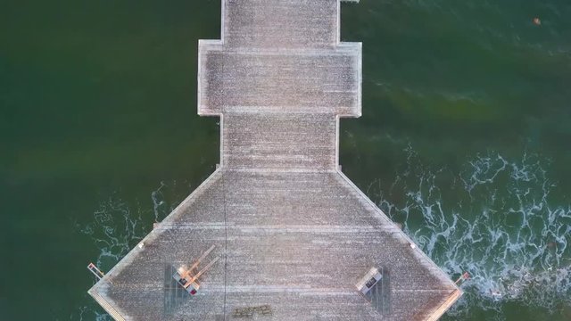 Beautiful aerial drone top down shot of the central portion of the wooden pier, isolated amidst the crashing waves in Pismo Beach, California