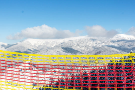 Ski resort Bukovel. Ukrainian Carpathians. Safety fence for security. Multicolored mesh to attract attention. The rules of skiing and snowboarding. Warning of danger. Winter landscape.
