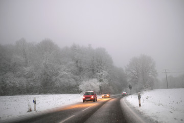 Autos im Schneetreiben auf glatter Fahrbahn - Stockfoto