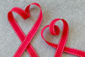 Two hearts made from red ribbon on linen textile, Valentine's Day concept.