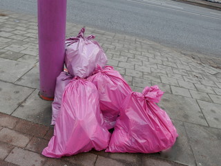 Stuffed and tied pink garbage bags on the roadside ready to be picked up