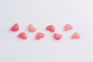 Valentine's Day concept made of heart shaped vibrant pink jelly sweets lined on white background. Top view. Copy space.